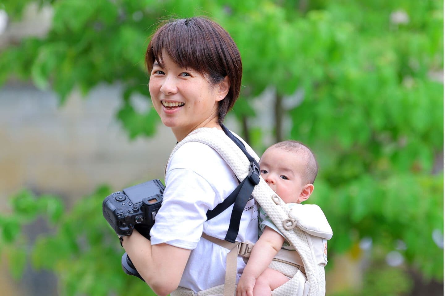 赤ちゃんをおんぶしてカメラを持ってる女性